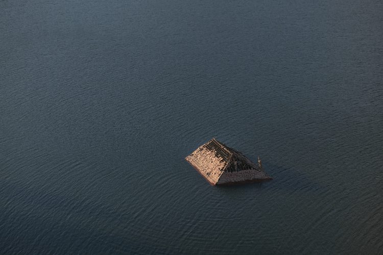 A roof of the ghost village sticks up above the surface of the reservoir.